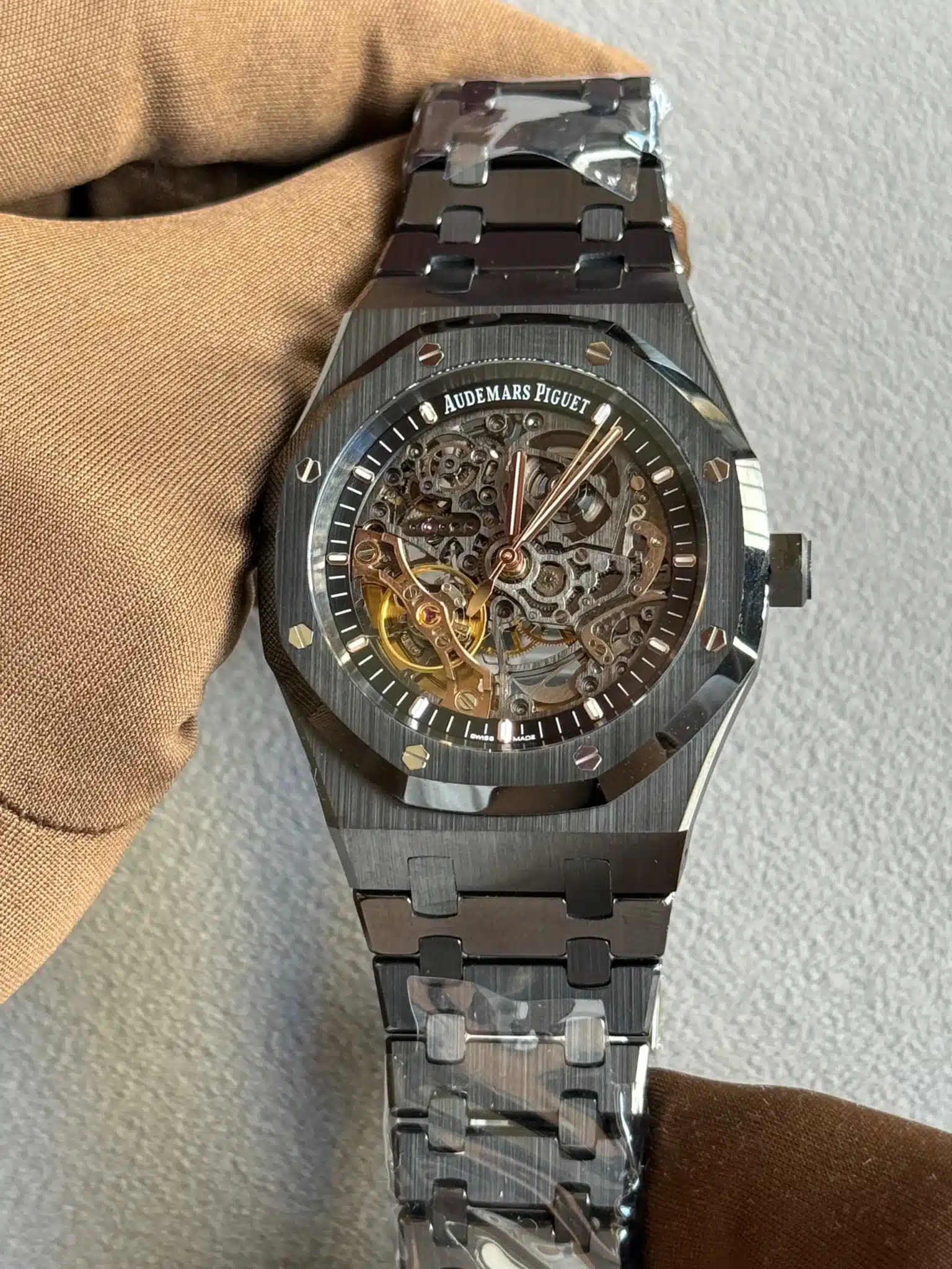 Skeleton-style Audemars Piguet wristwatch with visible gears through a transparent dial on a metal bracelet