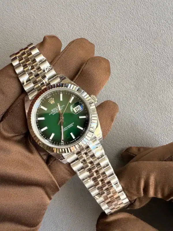 Rolex Datejust with a green dial and stainless steel jubilee bracelet, held by a brown-gloved hand.