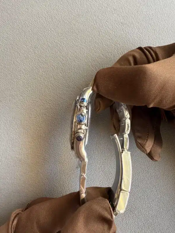 Close-up of a silver bracelet with blue stones resting on a brown fabric sleeve against a textured gray background.