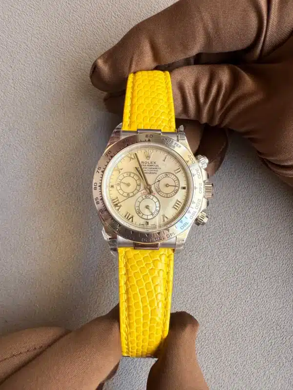 Rolex watch with a bright yellow embossed strap being held by gloved hands on a gray background.