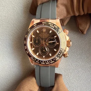 IMG_6621 - Ticker24Watches Ticker24Watches - Rose gold Rolex Daytona with black dial and tachymeter bezel, on a gray rubber strap, held by brown gloves.