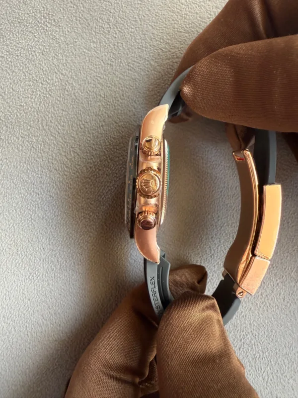 Close-up of a rose-gold wristwatch with a textured crown and side buttons resting on brown fabric background.
