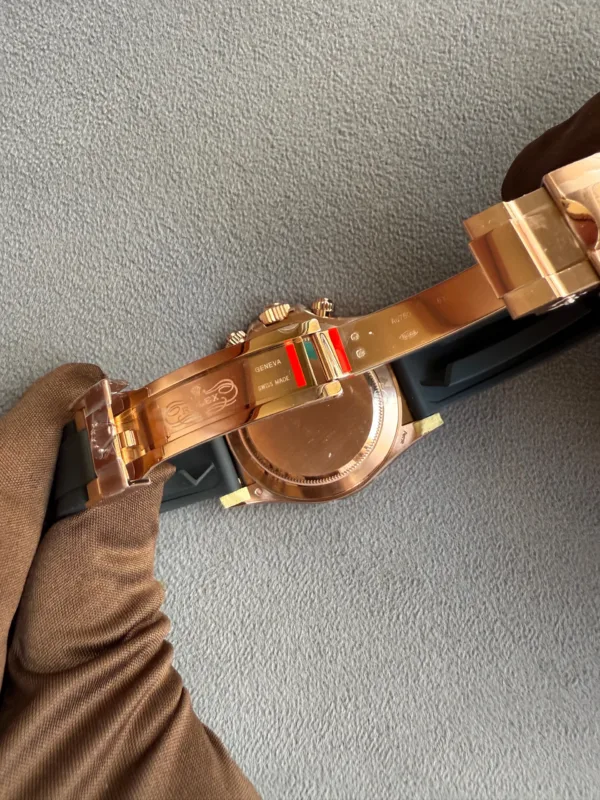 Rose-gold wristwatch with metal link band lying on a textured gray surface, brown sleeve visible nearby.