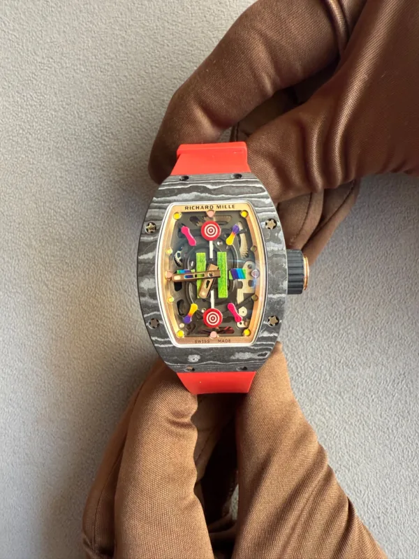 Skeleton dial Richard Mille wristwatch with orange strap worn on a gloved hand, showing colorful inner gears.