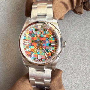 Stainless steel Rolex watch with a multicolored geometric-pattern dial and silver indices, held by a gloved hand against a gray background.
