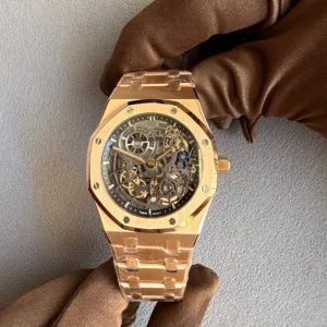 Rose-gold skeleton wristwatch held by a brown-gloved hand, exposing the gears through the transparent dial.