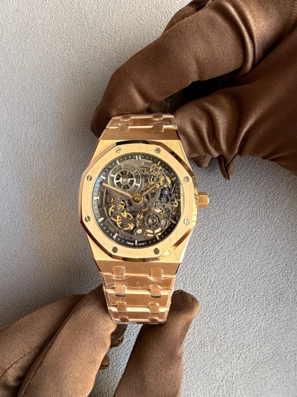 Rose-gold skeleton wristwatch held by a brown-gloved hand, exposing the gears through the transparent dial.