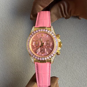 Pink Rolex watch with gold case and diamond-encrusted bezel held by a gloved hand on a gray fabric background, showcasing luxury details? No, this is the intended ALT.