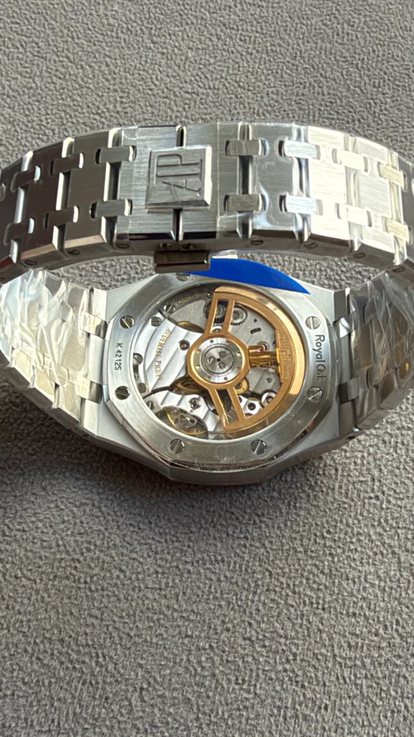 Stainless steel wristwatch with a visible mechanical movement and gold rotor, Royal Oak branding on the back, metal link bracelet visible.
