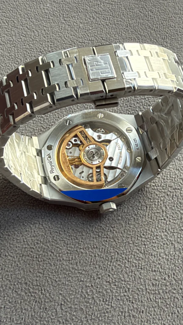 Stainless steel wristwatch back with visible gold rotor and inner mechanical movement visible through the transparent case back, bracelet links around it