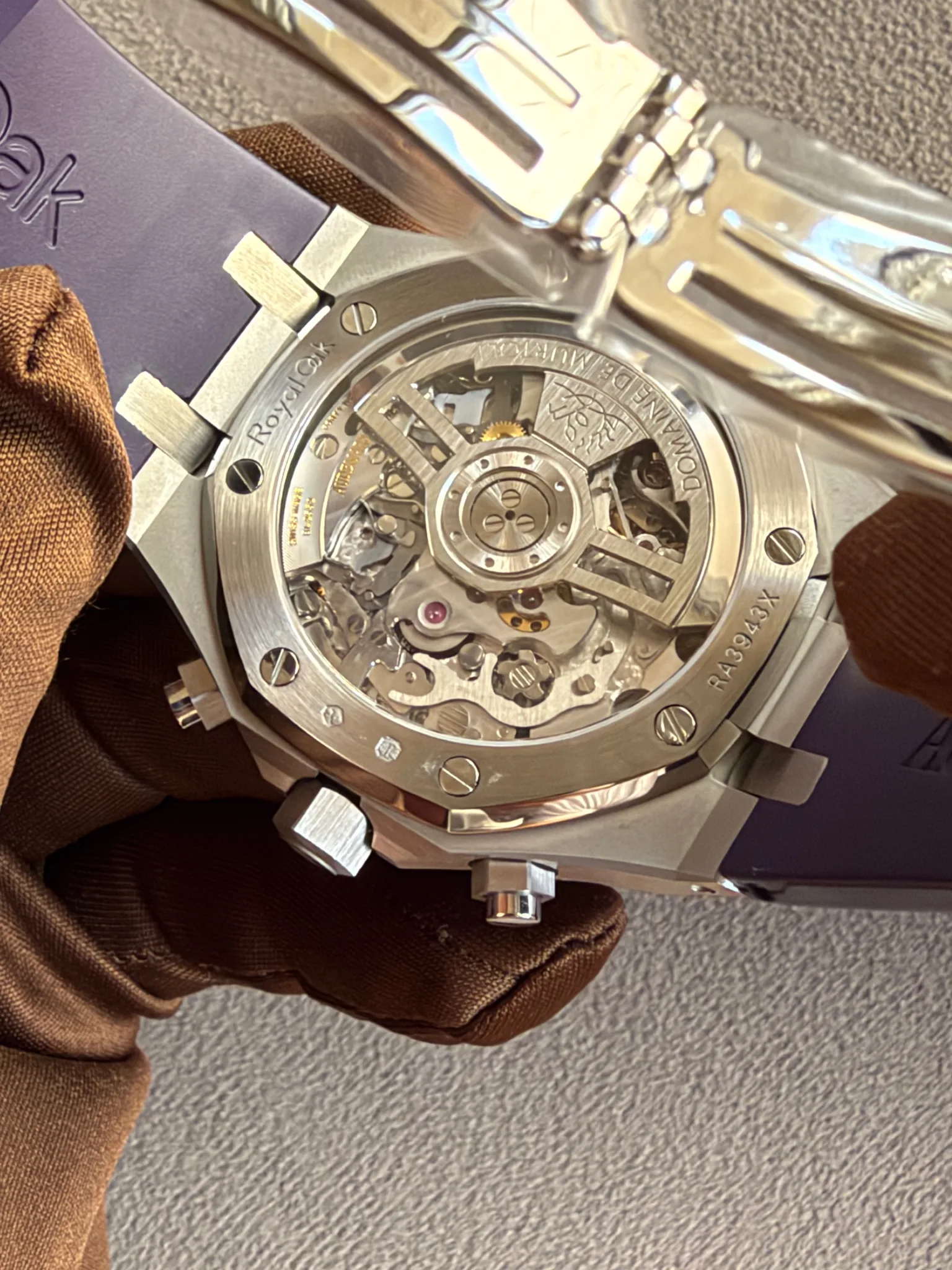 Open-back view of a stainless steel Royal Oak watch showing its automatic movement and rotor visible through a clear caseback