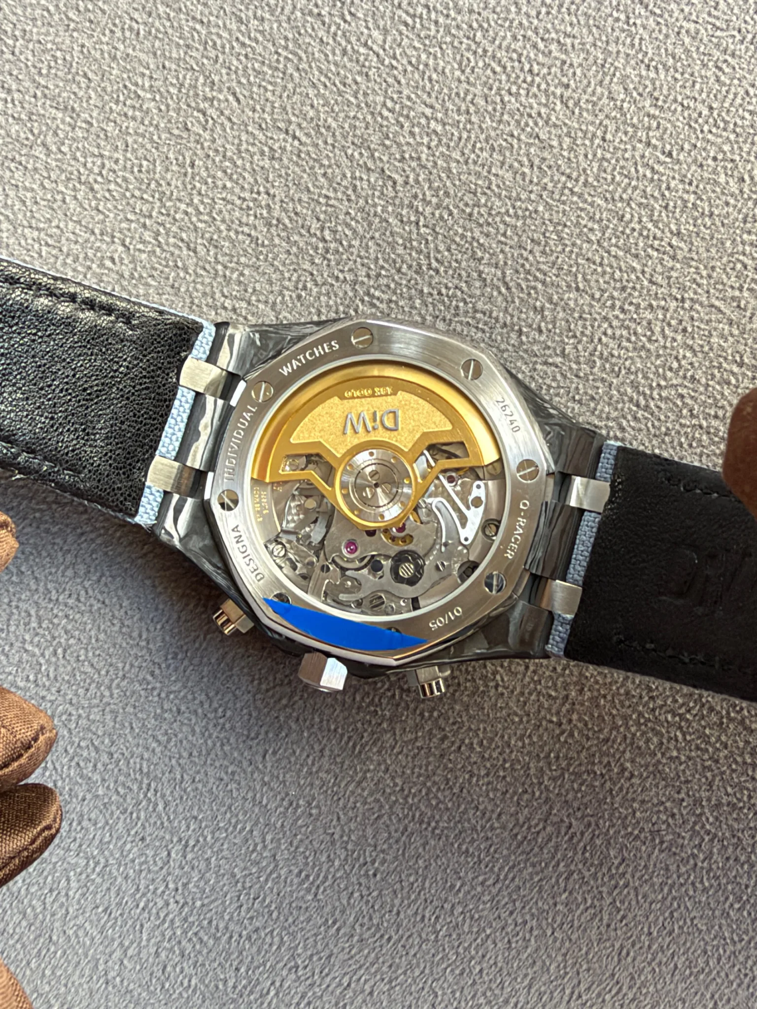 Watch back with transparent case showing a gold rotor and inner gears of a mechanical movement.