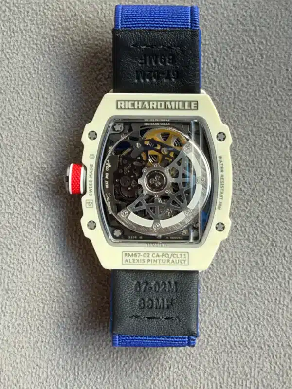 Richard Mille skeleton watch with cream case and blue strap, exposed gears visible through a clear caseback, on grey fabric.